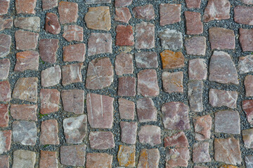 Stone granite cobblestoned pavement background or texture. Abstract background of old cobblestone pavement close-up in Prague