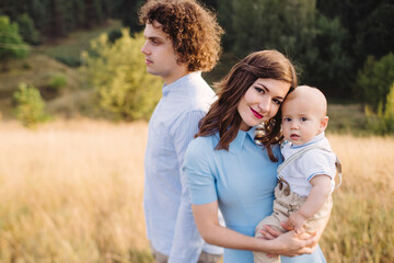 Young happy caucasian couple with little baby boy. Parents and son walking and having fun together. Mother and father playing with toddler outdoors. Family, parenthood, childhood, happiness concept.