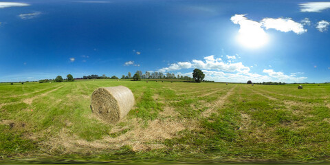 
360 degrees spherical panorama of beautiful green meadow with straw bales under blue sky
