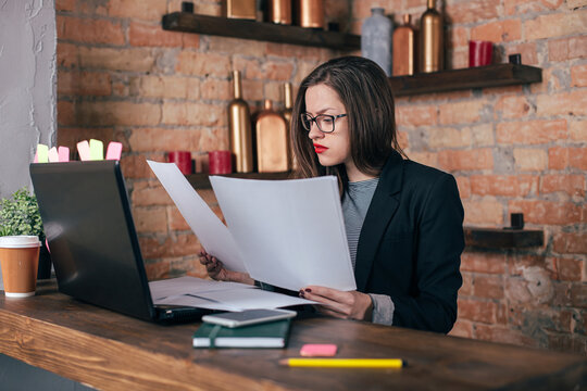 Young freelancer girl is working hard in laptop in loft interior