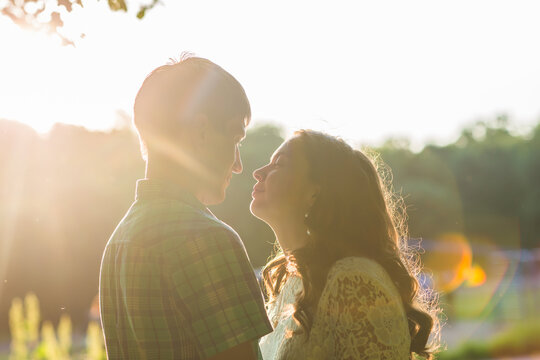 Closeup photo of romantic kissing couple outdoors, side view.