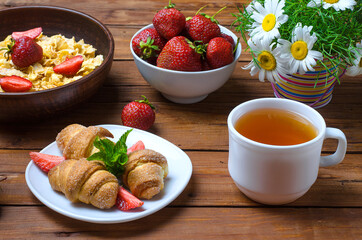 Healthy breakfast: corn flakes, strawberries, tea and croissant.