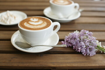 Two cups of cappuccino on a wooden table.