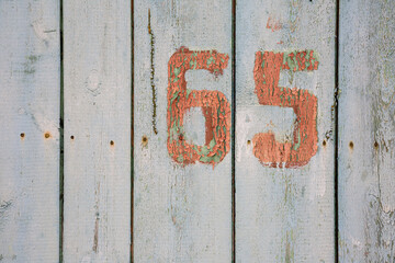 number 65 on aged white wooden planks