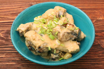 Chicken drumsticks in a bowl under creamy sauce