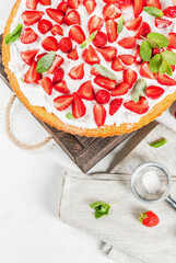 Homemade biscuit cake with whipped cream, fresh organic raw strawberries and mint. On a white stone table. Copy space top view