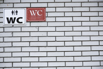 Fototapeta na wymiar Toilet sing for man and female on white brick wall