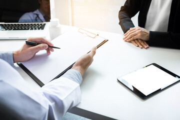 Healthcare and Medical concept, patient listening intently to a female doctor explaining patient symptoms or asking a question as they discuss paperwork together in a consultation