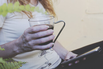 closeup of hands with a cup of coffee and mobile phone