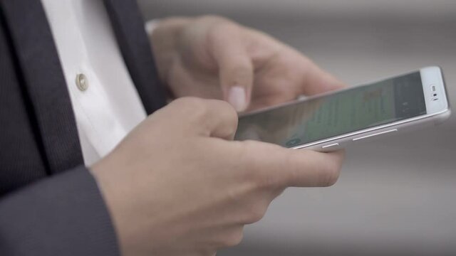 Girl in a business suit typing a message in a group chat on a smartphone. She prints quickly with two hands and sends the message to the abonent. UHD 4K