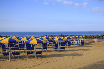 Fototapeta na wymiar Beach with umbrellas at the first light of day in Italy