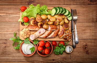 Grilled sausages and vegetables on the wooden board.