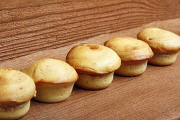 Sweet muffins on wooden background baked in form.