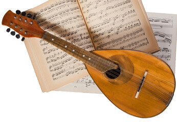 Vintage mandolin on a background of open sheet music book.
