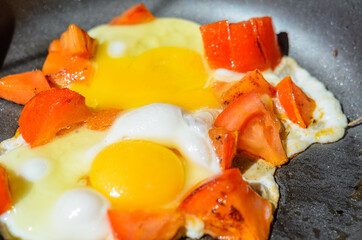 Scrambled eggs with roasted tomatoes/Scrambled eggs with tomato in a frying pan. The process of preparing breakfast