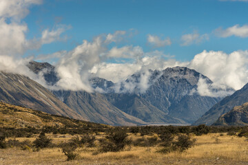 Middle Earth, New Zealand - March 14, 2017: High mountain range around Rock of Middle Earth  under blue sky with white clouds. Set in a high desert mountainous scenery.