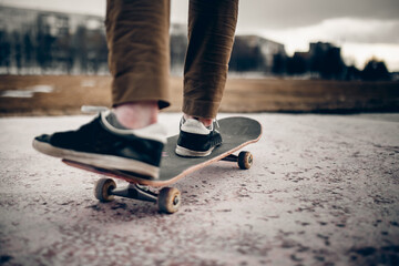 Man male skateboarder on a skateboard is riding in the sunset on the road, close-up. Concept street sport in holey boots.