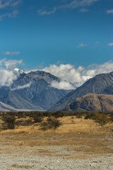 Middle Earth, New Zealand - March 14, 2017: Portrait of Snow capped High mountain range around Rock of Middle Earth under blue sky with white clouds. Set in a high desert mountainous scenery.