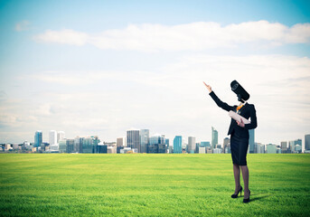Camera headed woman standing on green grass against modern citys