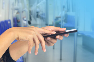 Close up of woman hands holding cell phone with blurred of subway background