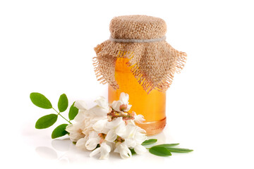 Jar of honey with flowers of acacia isolated on white background