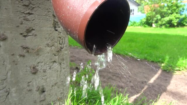 Rain gutter draining water away from a roof, slow motion