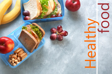 Lunchboxes with sandwiches and different products on grey background