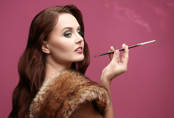 Obraz premium Beautiful woman smoking cigar on color background