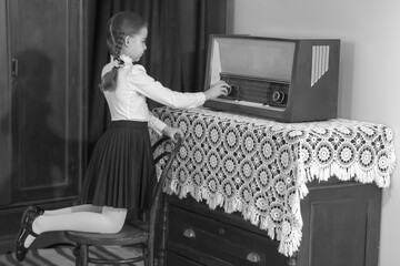 Little girl listens to old radio.