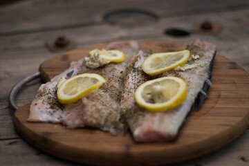fresh fish with herbs and limon laying on wooden table closeup