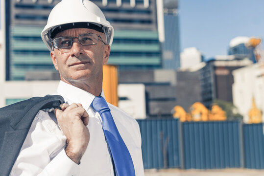 Senior elegant builder man in suit at construction site on sunny