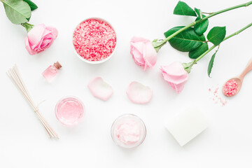 cosmetic set with rose blossom and body cream on white desk background top view