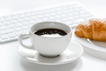 Office lunch with coffee and croissant, keyboard on white table background