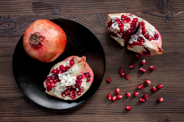 pomegranate seeds, sliced fruit on wooden background top view