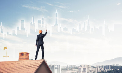Man architect draw silhouette of modern city on blue sky. Mixed 