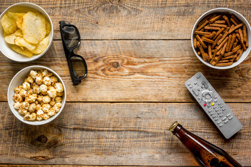 Fototapeta na wymiar cinema and TV whatching with beer, crumbs, chips and pop corn wooden background top view mock-up