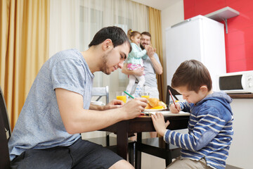 Obraz na płótnie Canvas Male gay couple with children having breakfast in kitchen
