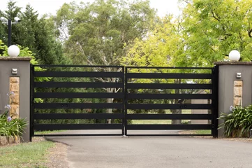 Fotobehang Black metal driveway entrance gates set in brick fence © squirrel7707