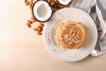 Delicious coconut pancakes decorated with almond shavings on table