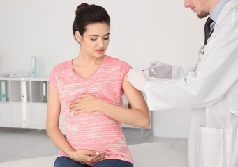 Young pregnant woman receiving injection from medical assistant in clinic
