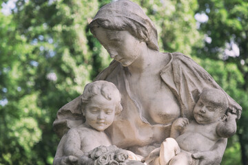 Young mother with little children monument on a tomb at a graveyard