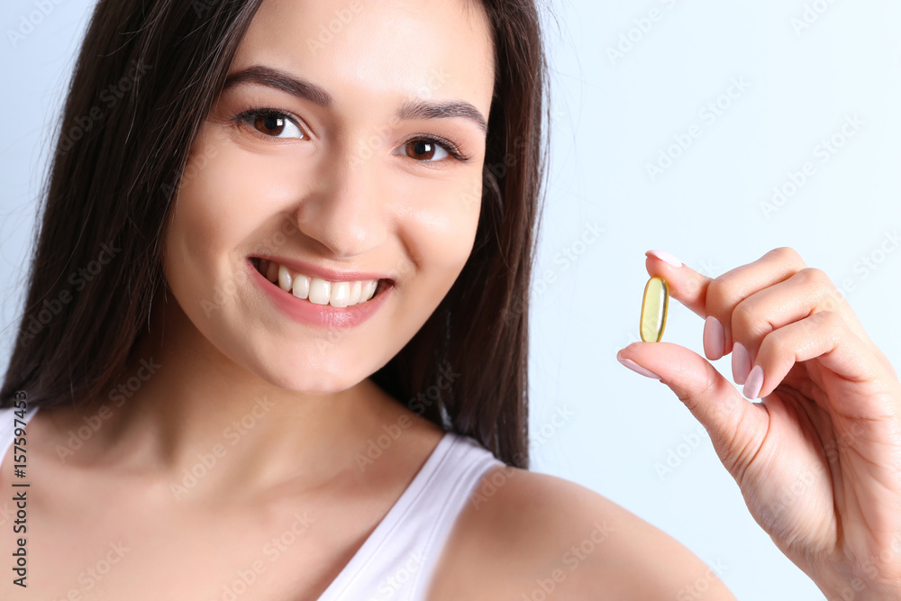 Wall mural woman taking fish oil pill on white background