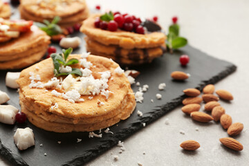 Stacks of delicious coconut pancakes with sweet sauce and shavings on slate plate, close up