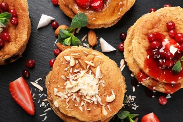 Deurstickers Stacks of delicious coconut pancakes with sweet sauce, berries, shavings and mint on slate plate, close up © Africa Studio