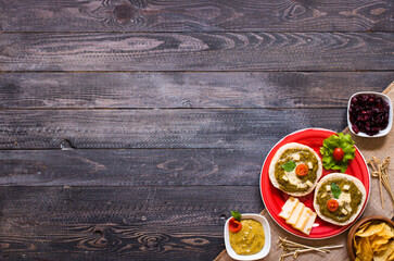 tasty and delicious bruschetta with avocado, tomatoes, cheese, herbs, chips and liquor, on a wooden background.