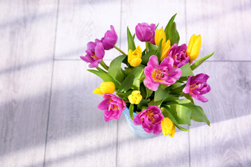 Vase with bouquet of beautiful tulips on floor
