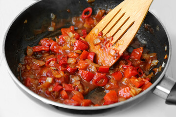 Frying pan with chopped onion and pepper on hot plate