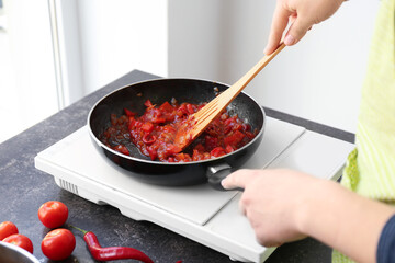 Woman frying chopped onion and pepper on kitchen, closeup