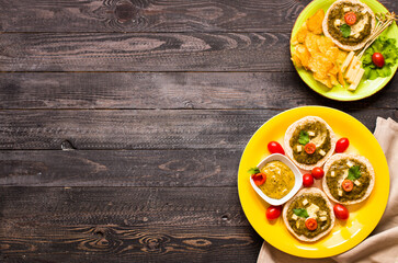 tasty and delicious bruschetta with avocado, tomatoes, cheese, herbs, chips and liquor, on a wooden background.