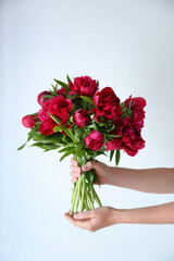Female hands holding peony bouquet on white background